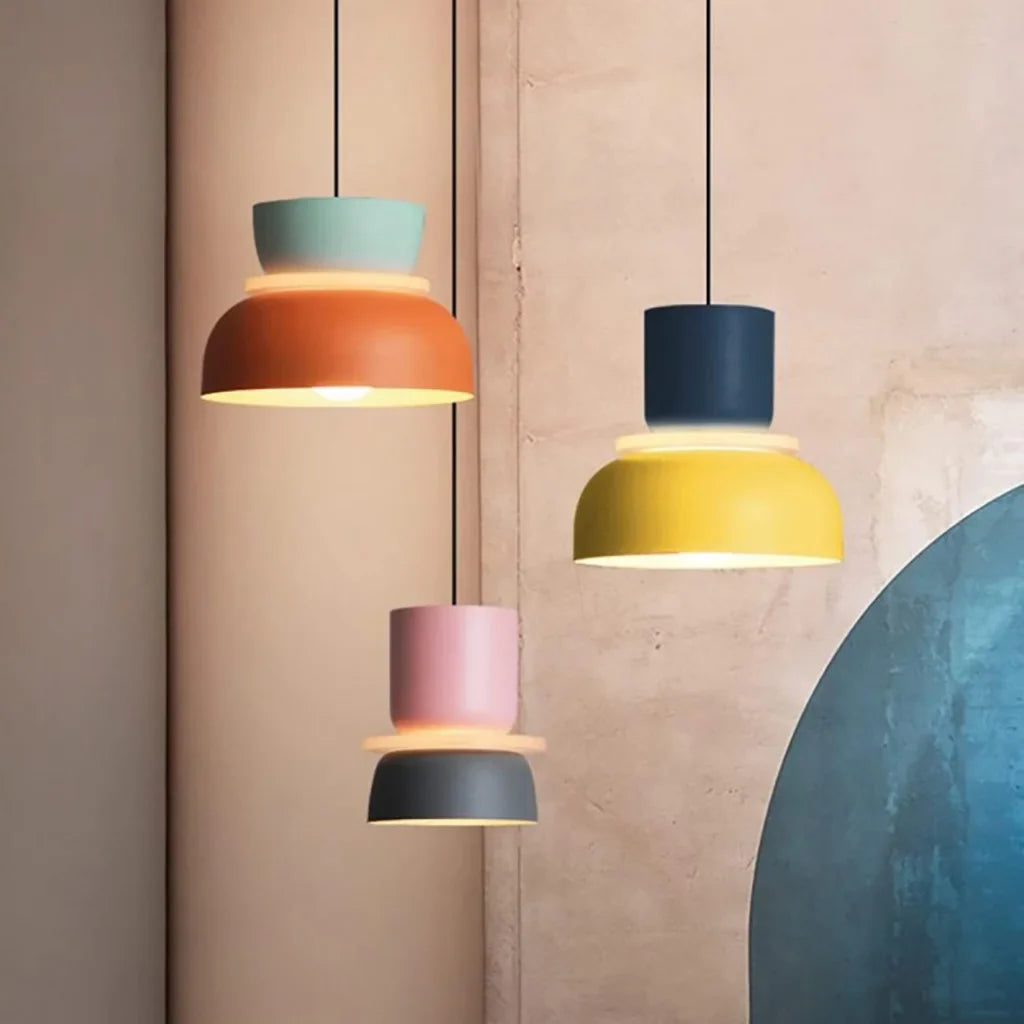 Three colorful pendant lights against a soft pink wall