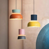 Three colorful pendant lights against a soft pink wall