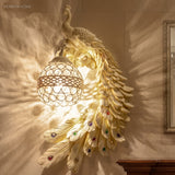 Ivory white peacock wall sconce mounted on a stone wall beside a gold frame