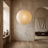 Ribbed washi paper globe pendant against a plaster wall and alcove