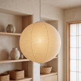 Washi paper globe pendant glowing beside shelves of ceramic vessels
