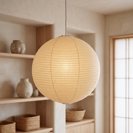 Washi paper globe pendant glowing beside shelves of ceramic vessels