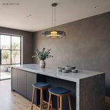 Grey tinted glass disc pendant light above a stone kitchen island