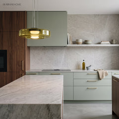 Amber glass disc pendant light in a modern kitchen with green cabinetry