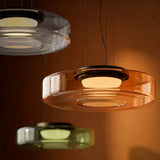 Amber two-layer glass pendant light lit against a warm brown wall