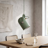 Green tilted spot pendant above a dining table with a carafe