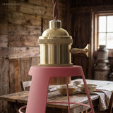 Close up of the brass socket above a pink stool in a barn kitchen