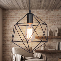 Black cage pendant with a filament bulb against an exposed brick wall