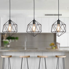 Three black cage pendants in a row above a white kitchen island