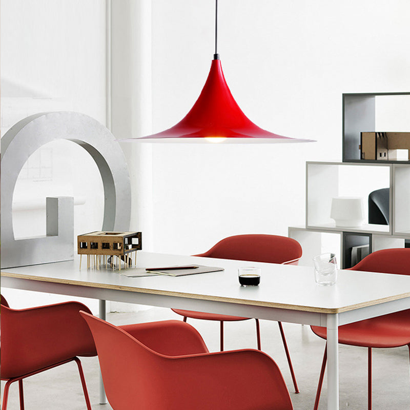 Red flared pendant above a white table with red dining chairs