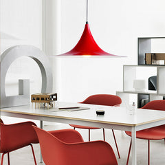 Red flared pendant above a white table with red dining chairs