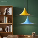 Yellow and blue flared pendants against a deep green painted wall