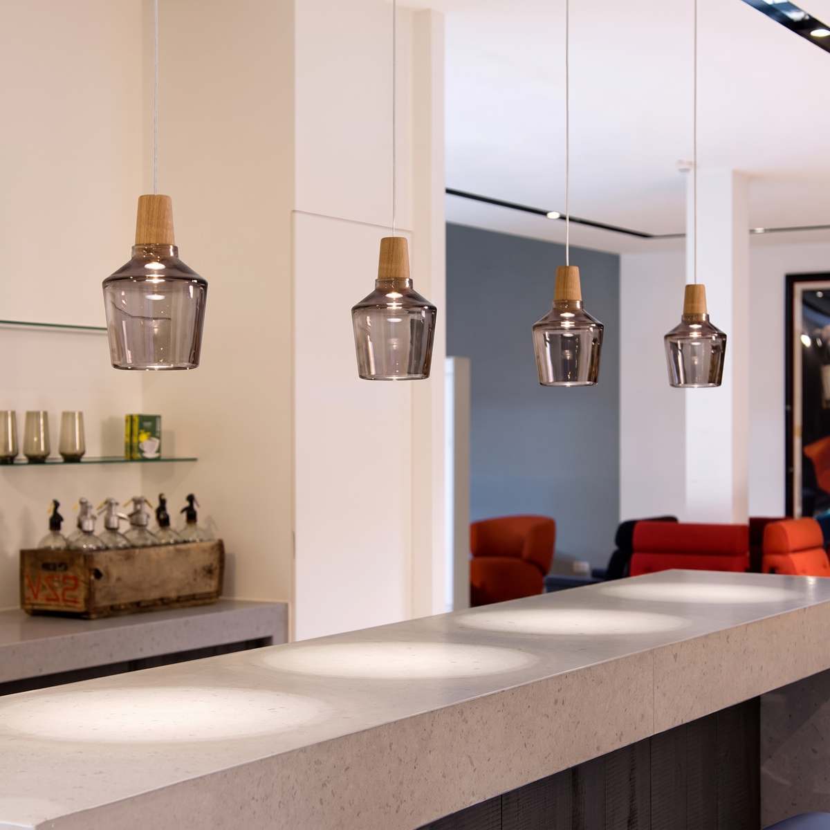 Amber glass pendants in a row above a light kitchen counter