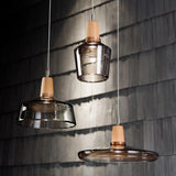 Three glass pendants hung against a dark timber shingle wall