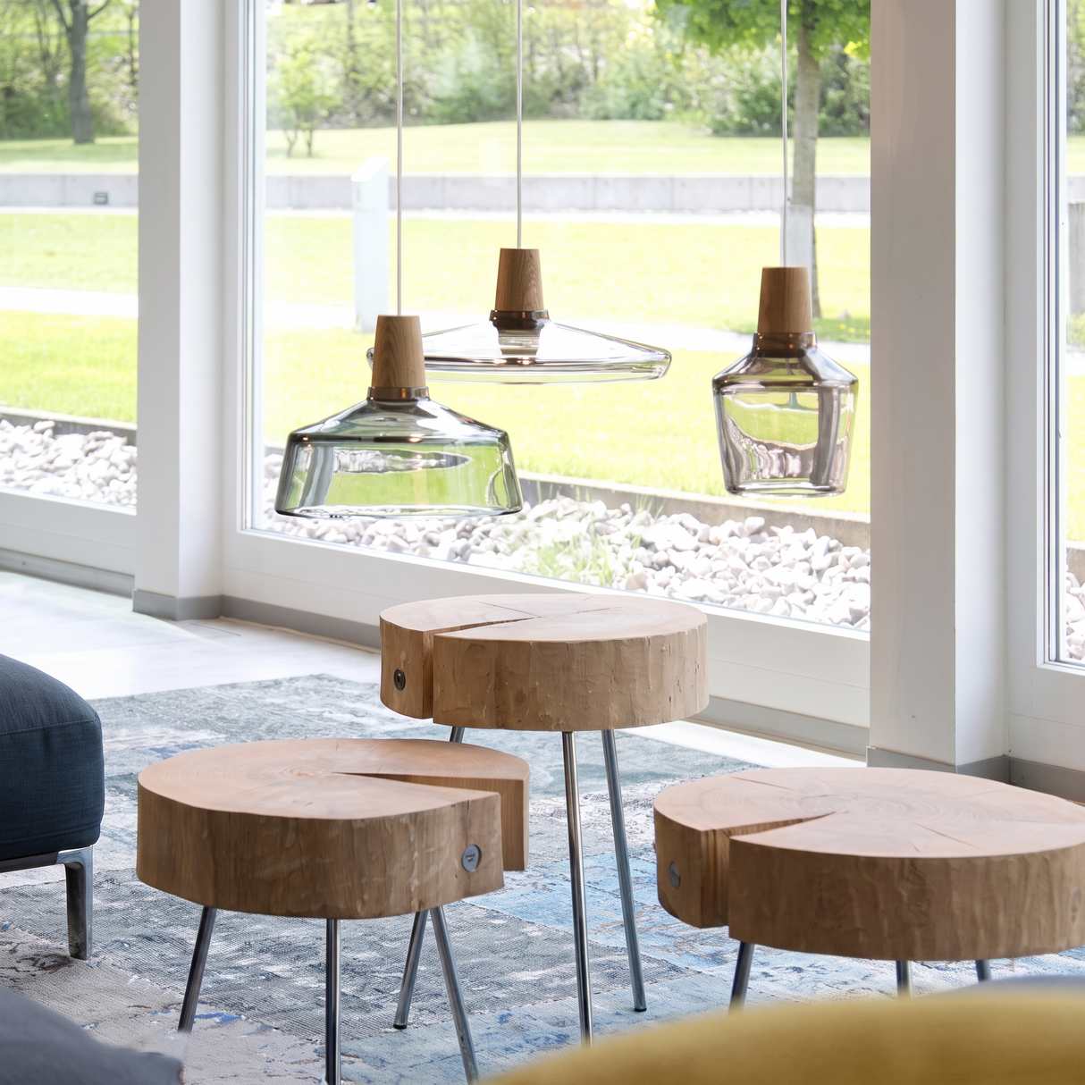 Glass pendants lit above timber stump tables beside tall windows