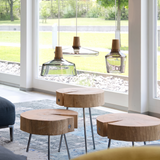 Glass pendants lit above timber stump tables beside tall windows