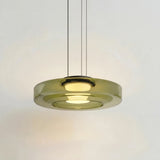 Green tinted glass disc pendant light glowing warmly on a studio background