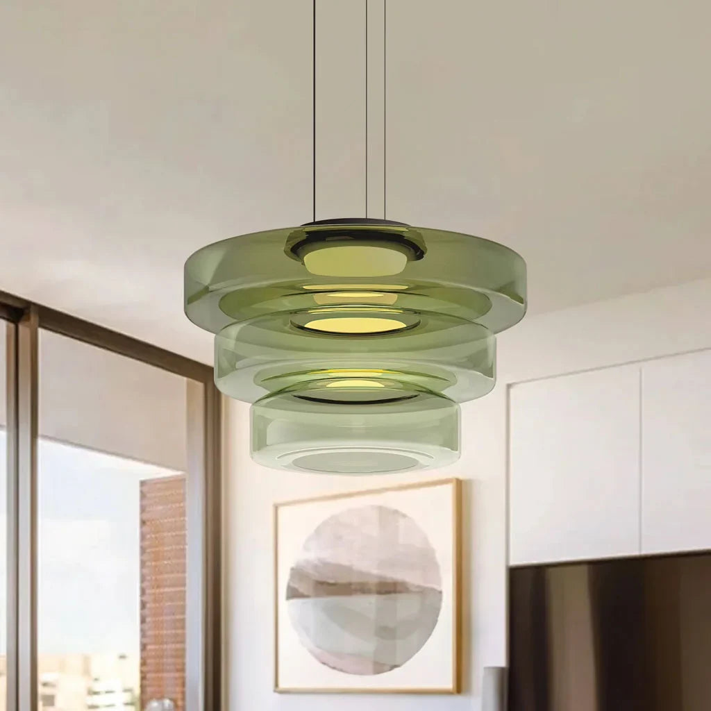 Green three-layer glass pendant light in a white kitchen with round artwork