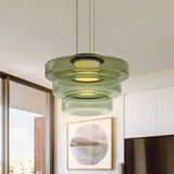 Green three-layer glass pendant light in a white kitchen with round artwork