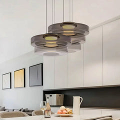 Cluster of smoke grey three-layer glass pendants over a white kitchen island