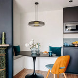 Smoke grey glass pendant light over a black table in a blue kitchen