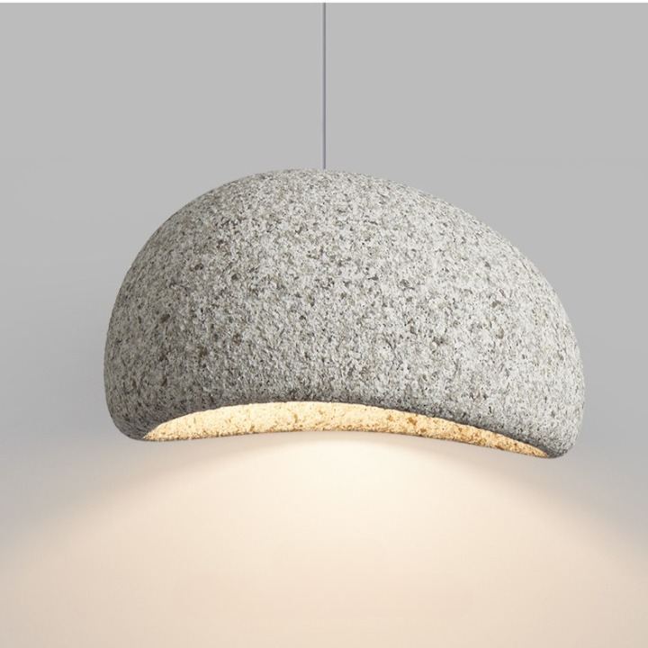 Grey speckled dome pendant lit warm against a pale wall