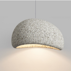 Grey speckled dome pendant lit warm against a pale wall