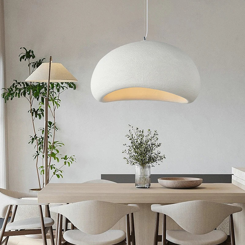 White dome pendant lit above a dining table and pale chairs