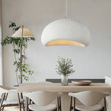 White dome pendant lit above a dining table and pale chairs