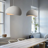Two white dome pendants lit above a long timber table