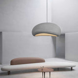 White dome pendant lit above a low sofa in a curved white room