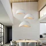 Two white dome pendants hanging in a tall double height space