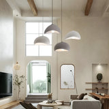 Three white dome pendants lit in a room with exposed beams