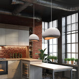 Two grey dome pendants lit above a kitchen island and brick wall