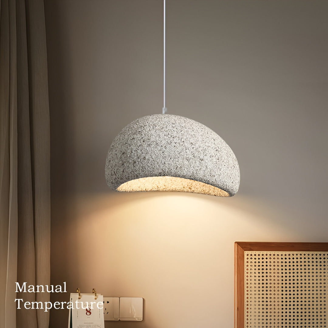 Grey dome pendant lit above a table with dried grasses