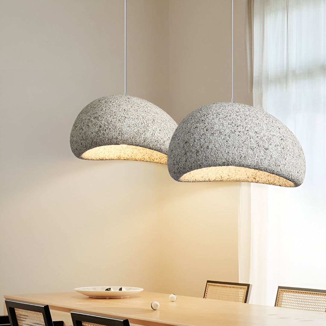 Two grey dome pendants lit above a long dining table