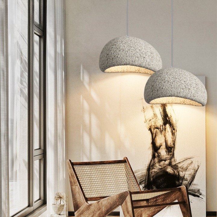 White dome pendant lit above a round table and cane chair