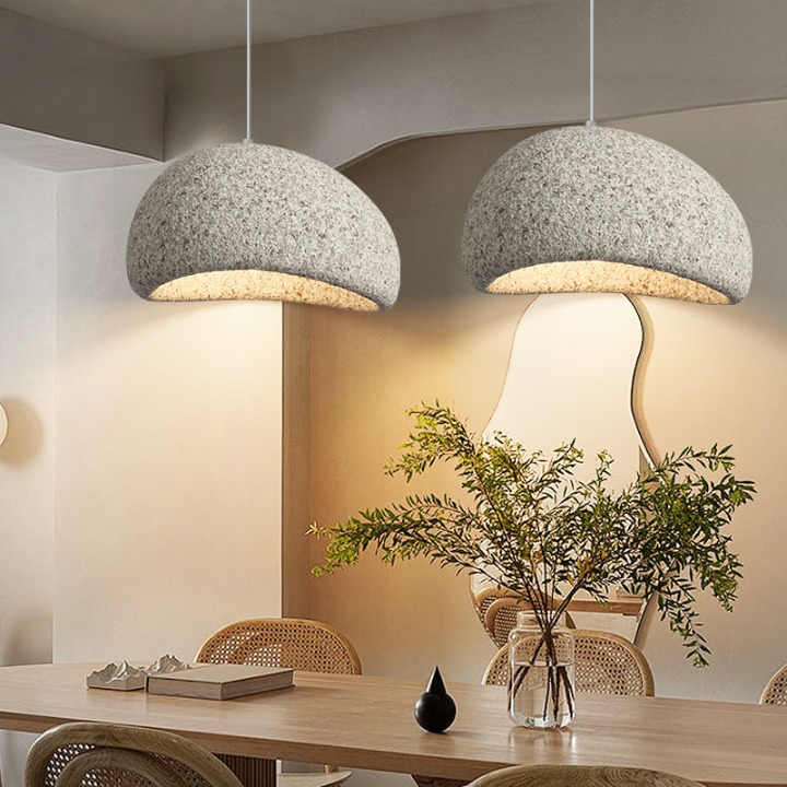 Two white dome pendants lit above a table with a plant