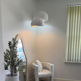 White dome pendant lit beside a mirror and potted olive tree
