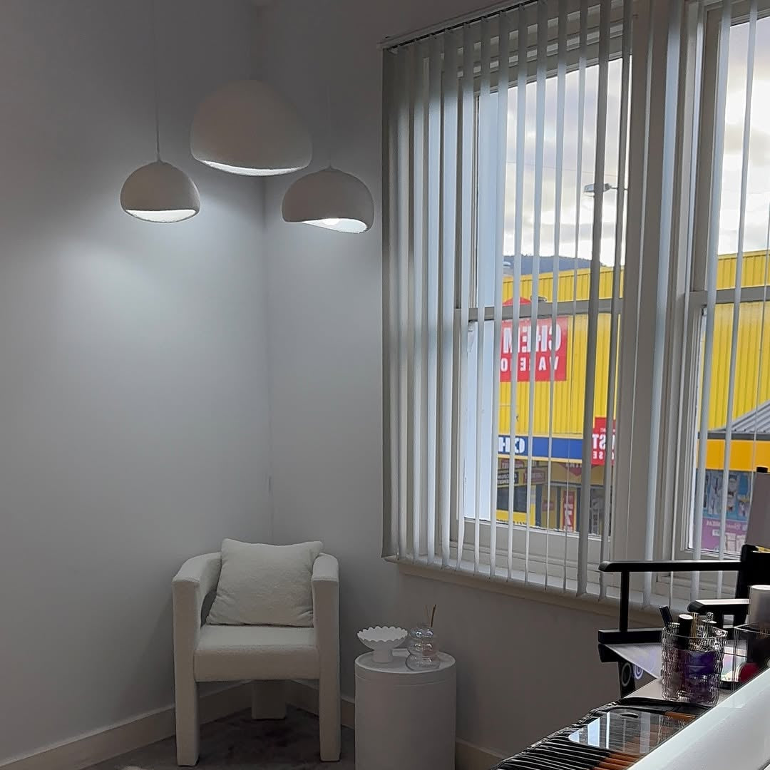 Three white dome pendants lit in a room with vertical blinds