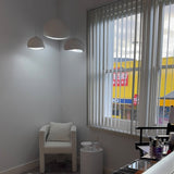 Three white dome pendants lit in a room with vertical blinds