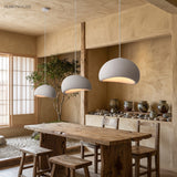 Three white wabi sabi pendants lit above a long dining table