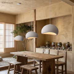 Three white wabi sabi pendants lit above a long dining table
