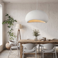 White wabi sabi pendant lit above a wooden dining table and chairs