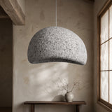 Grey wabi sabi dome pendant lit above a console in a plaster room