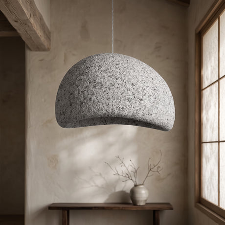 Grey wabi sabi dome pendant lit above a console in a plaster room
