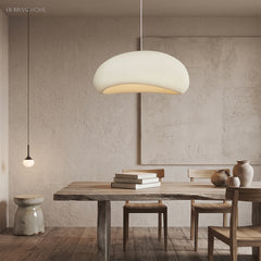 White wabi sabi pendant lit above a long table in a plaster room