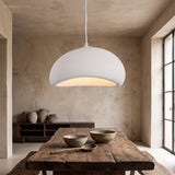White dome pendant lit above a rustic timber dining table
