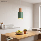 Green metal pendant hanging above a light oak kitchen island