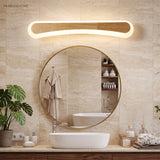 Curved wood vanity light lit above a round mirror and vessel basin